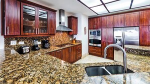 Una cocina con encimeras de granito, gabinetes de madera, electrodomésticos de acero inoxidable y un tragaluz.