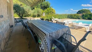 Un espace extérieur aménagé pour les repas, avec un patio couvert, une piscine et une vue sur le paysage.