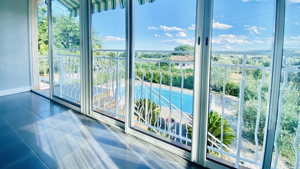 Un balcon avec vue sur une piscine et sur la verdure.