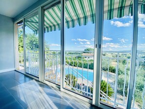 Un balcón con vista a una piscina y follaje.