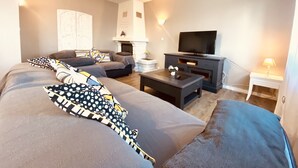 Un salon moderne avec un canapé, un téléviseur et une cheminée.