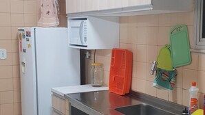 Eine kleine Küche mit Kühlschrank, Mikrowelle und Spüle.