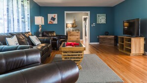 A living room with a leather sofa, wooden coffee table, and a TV stand. - Located Directly On Rockland Harbor (Rockland)