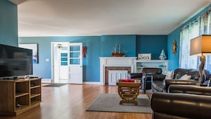 A living room with a fireplace, a television, and a leather sofa. - Located Directly On Rockland Harbor (Rockland)