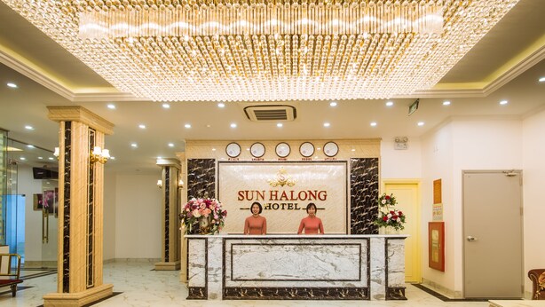 Zona de recepción con mostrador de mármol, una araña y el cartel del Hotel Sun Halong.