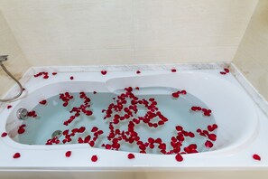 A bathtub filled with water and rose petals. - Sun Halong Hotel (Ha Long)