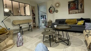 A living room with a sofa, a coffee table, and a dining area. There is a mirror on the wall and a painting above the sofa. - house between vineyards and garrigue (Vénéjan)