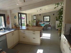 A modern kitchen with white cabinetry, a wooden countertop, and a dining area with a table and chairs.