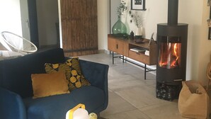 A living room with a sofa, a table with decorative items, a fireplace, and a wooden cabinet. - house between vineyards and garrigue (Vénéjan)