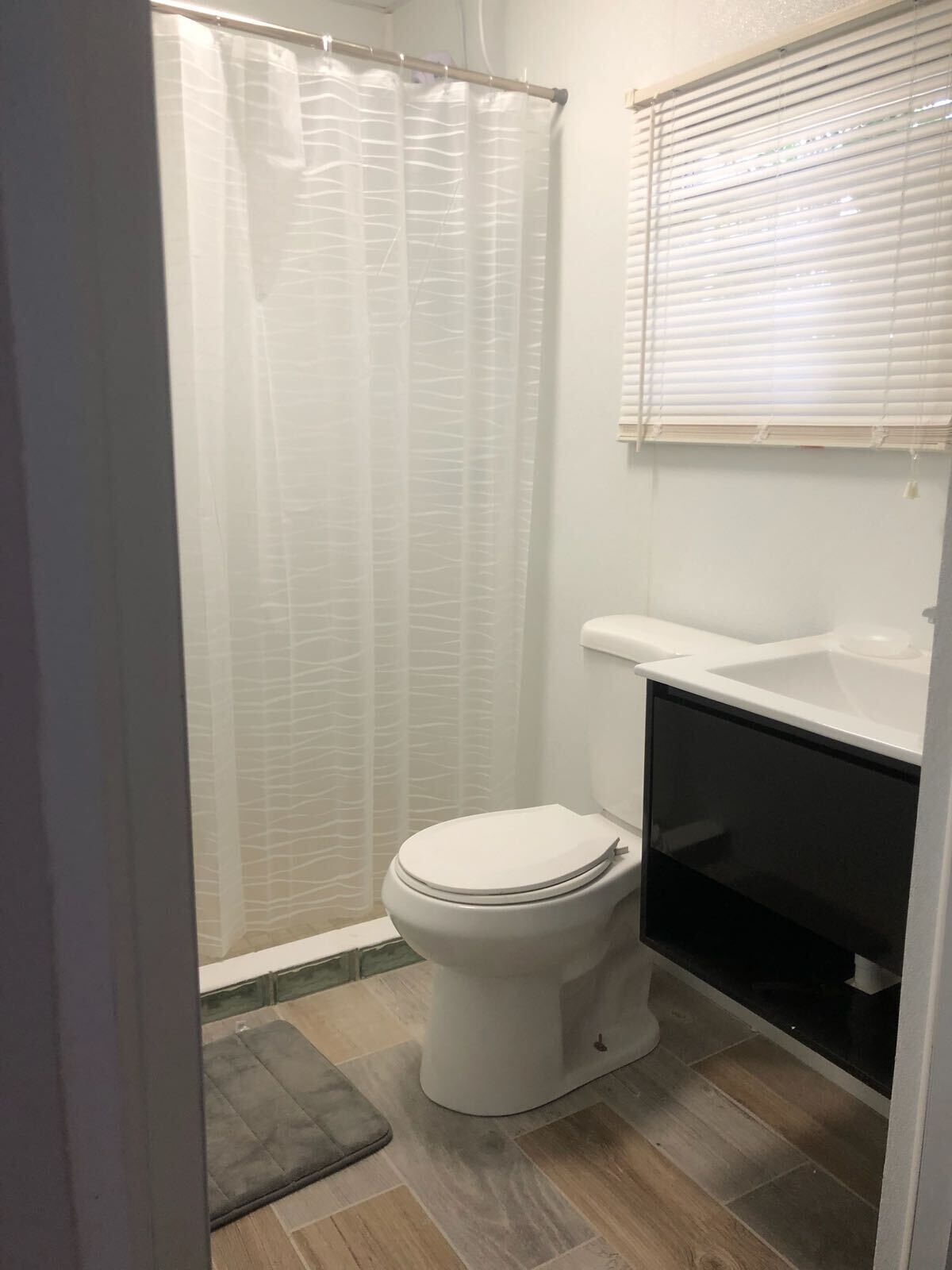 A small, modern bathroom with a toilet, a sink, and a shower curtain.