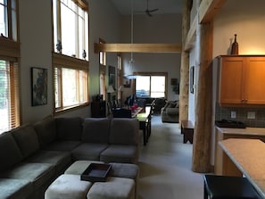 A spacious living area with a large sofa, a dining table, and a kitchen area with wooden cabinets. - Vacation Penthouse Condo in a Ski and Mountain Bike Resort (Red Mountain Village)