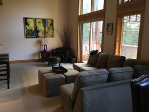 A living room with a sofa, ottoman, and a coffee table. There is a chair, a lamp, and a painting on the wall. - Vacation Penthouse Condo in a Ski and Mountain Bike Resort (Red Mountain Village)