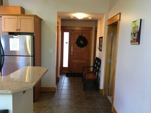 A kitchen with a refrigerator, a wooden door with a wreath, a chair, and a wall with a picture. - Vacation Penthouse Condo in a Ski and Mountain Bike Resort (Red Mountain Village)