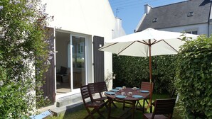 Una veranda con un tavolo apparecchiato per quattro persone, circondata da sedie e ombrellone per l'ombra.