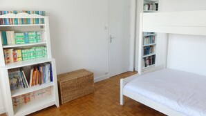 Una stanza con un letto a castello, una libreria e un piccolo cesto di vimini.