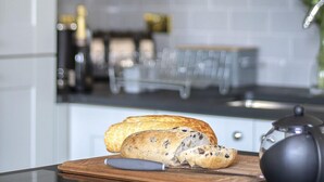 A kitchen counter with a cutting board holding sliced bread and a teapot.