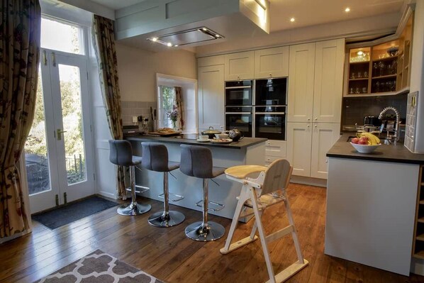 A modern kitchen with white cabinets, a central island with bar stools, and built-in appliances.