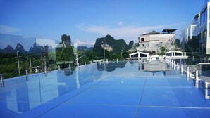A modern building with a glass facade, a flat roof, and a view of a mountainous landscape. - Yangshuo Lightheart Homestay (Guilin)
