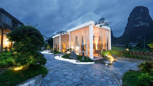 A modern building with a glass facade, surrounded by a stone pathway and greenery. - Yangshuo Lightheart Homestay (Guilin)