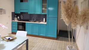 A compact kitchen with teal cabinets, a white countertop, and a patterned floor. - DORIDE Apartment on the beach (Balestrate)