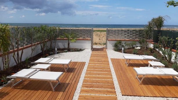 A wooden deck with white lounge chairs and a view of the beach. - DORIDE Apartment on the beach (Balestrate)