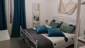 A bedroom with a bed, a bedside table, a hanging light fixture, a mirror, and a wall-mounted air conditioner. - DORIDE Apartment on the beach (Balestrate)