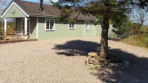 A single-story house with a gravel driveway and a large tree in front. - Peaceful, relaxing  lodge for 2 set in countryside (Elgin)