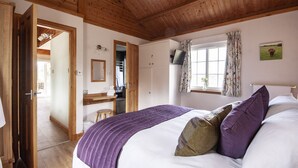A bedroom with a wooden ceiling, a bed with a purple blanket, a window with curtains, and a television on a stand. - Peaceful, relaxing  lodge for 2 set in countryside (Elgin)