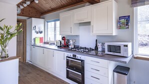 A modern kitchen with white cabinets, a built-in oven, a microwave, and a gas stove. - Peaceful, relaxing  lodge for 2 set in countryside (Elgin)