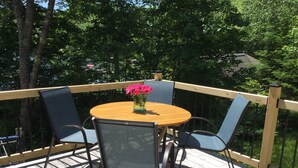 A wooden deck with a round table and four chairs, surrounded by a wooden railing. - Pond House - Donnell's Pond in Franklin, Maine (Franklin)