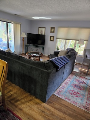 A living room with a sofa, a television, a lamp, and a window with curtains. - New Listing!! Lovely three bedroom home in Sea Pines Hilton Head. New addition.  (Hilton Head Island)