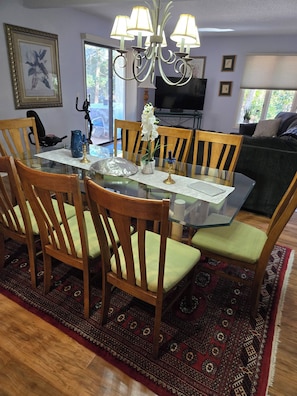 A dining area with a glass table, wooden chairs, a chandelier, and a patterned rug. - New Listing!! Lovely three bedroom home in Sea Pines Hilton Head. New addition.  (Hilton Head Island)