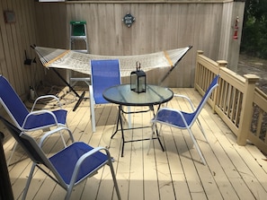 A covered outdoor patio with a table and blue chairs, a hammock, and a ladder against a wooden wall. - New Listing!! Lovely three bedroom home in Sea Pines Hilton Head. New addition.  (Hilton Head Island)