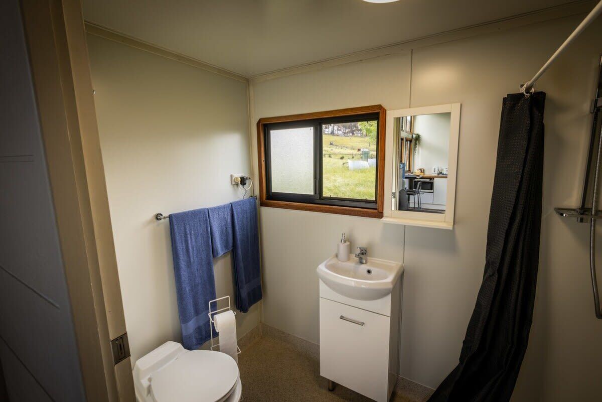 Een kleine badkamer met toilet, wastafel en een raam.