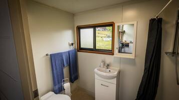 Een kleine badkamer met toilet, wastafel en een raam.