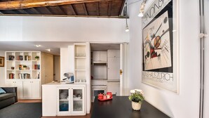 Eine moderne Küche mit weißen Schränken, einem schwarzen Esstisch und einem gerahmten Bild an der Wand.