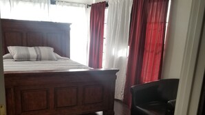 Une chambre à coucher avec un lit en bois, une chaise et une petite table en bois.