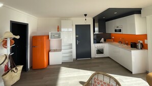 A compact kitchen with white cabinets, a black door, and a small oven. - Spacious T3 with large terrace SEA VIEW (Le Grau-du-Roi)