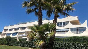 A modern building with a unique architectural design, featuring multiple balconies and large windows. - Spacious T3 with large terrace SEA VIEW (Le Grau-du-Roi)