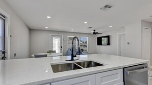 Cozinha moderna com uma ilha grande, eletrodomésticos de aço inoxidável e um ventilador de teto.