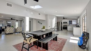 Uma sala de estar espaçosa com uma mesa de jantar de madeira escura, um tapete estampado em vermelho e um ventilador de teto.