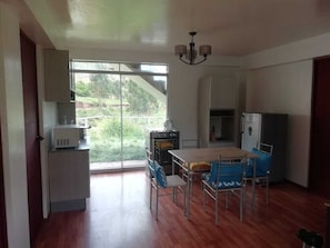A spacious kitchen with a dining area, large windows, and a view of greenery. - Hacienda Cachimayo, Cusco (Cachimayo)