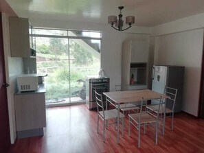 A modern kitchen with a dining area, large windows, and a view of greenery outside. - Hacienda Cachimayo, Cusco (Cachimayo)