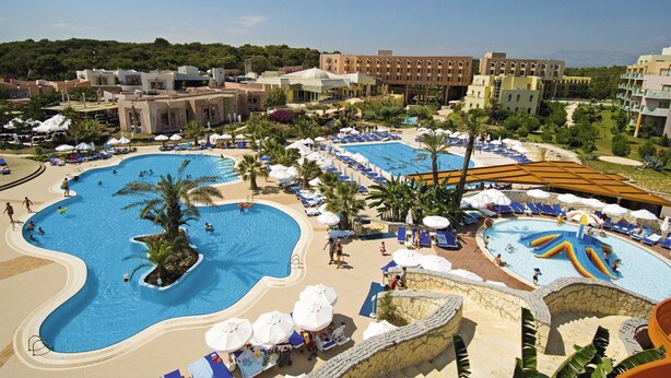 Un complexe hôtelier doté de plusieurs piscines, de chaises longues et de palmiers.