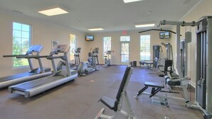 Une salle de sport équipée de tapis de course, de vélos elliptiques et de matériel de musculation.