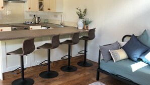Une cuisine moderne dotée d’un îlot central, de tabourets de bar, d’un canapé et d’une table basse.