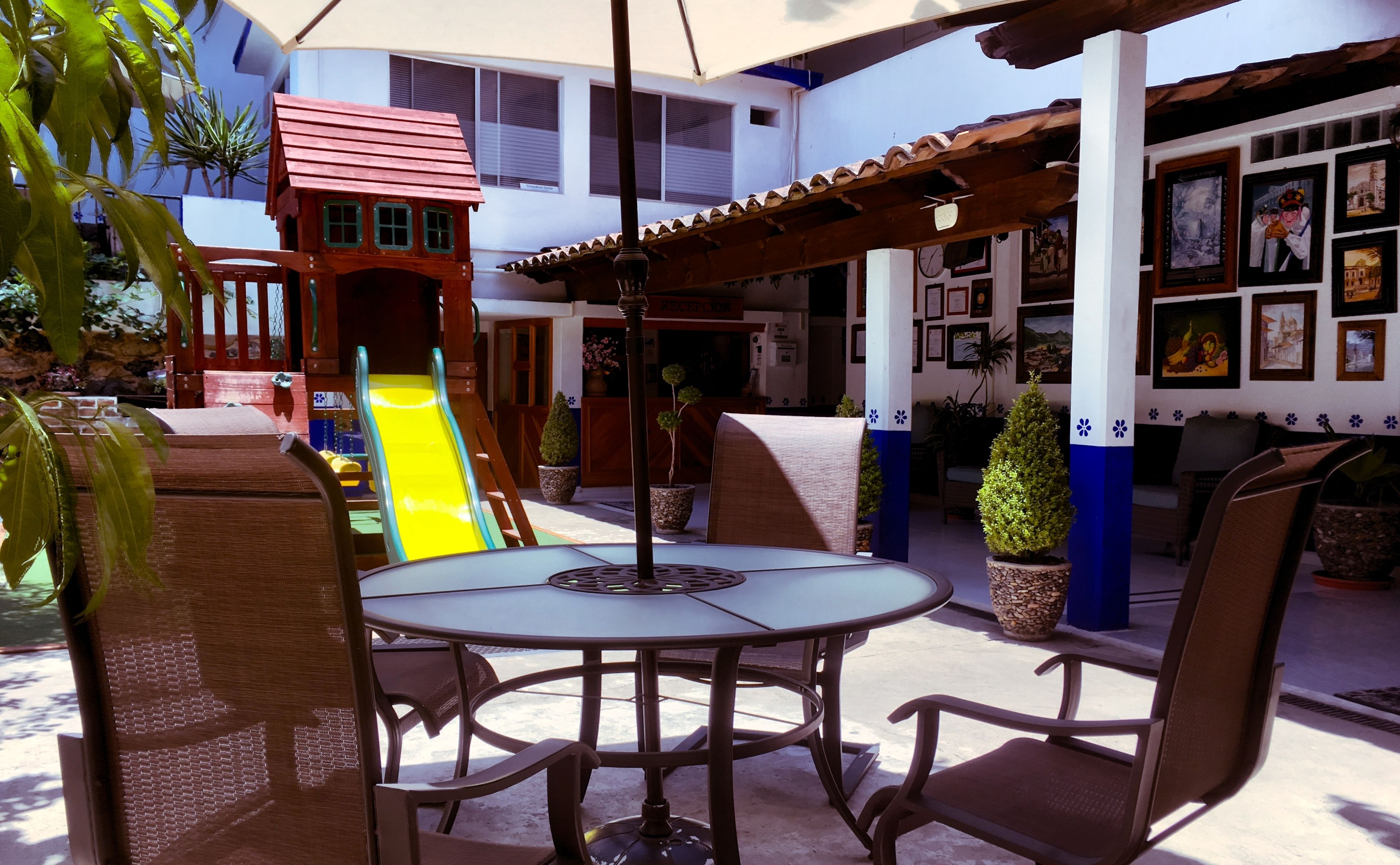 A patio area with a round table and chairs, a children's playhouse, and a slide.