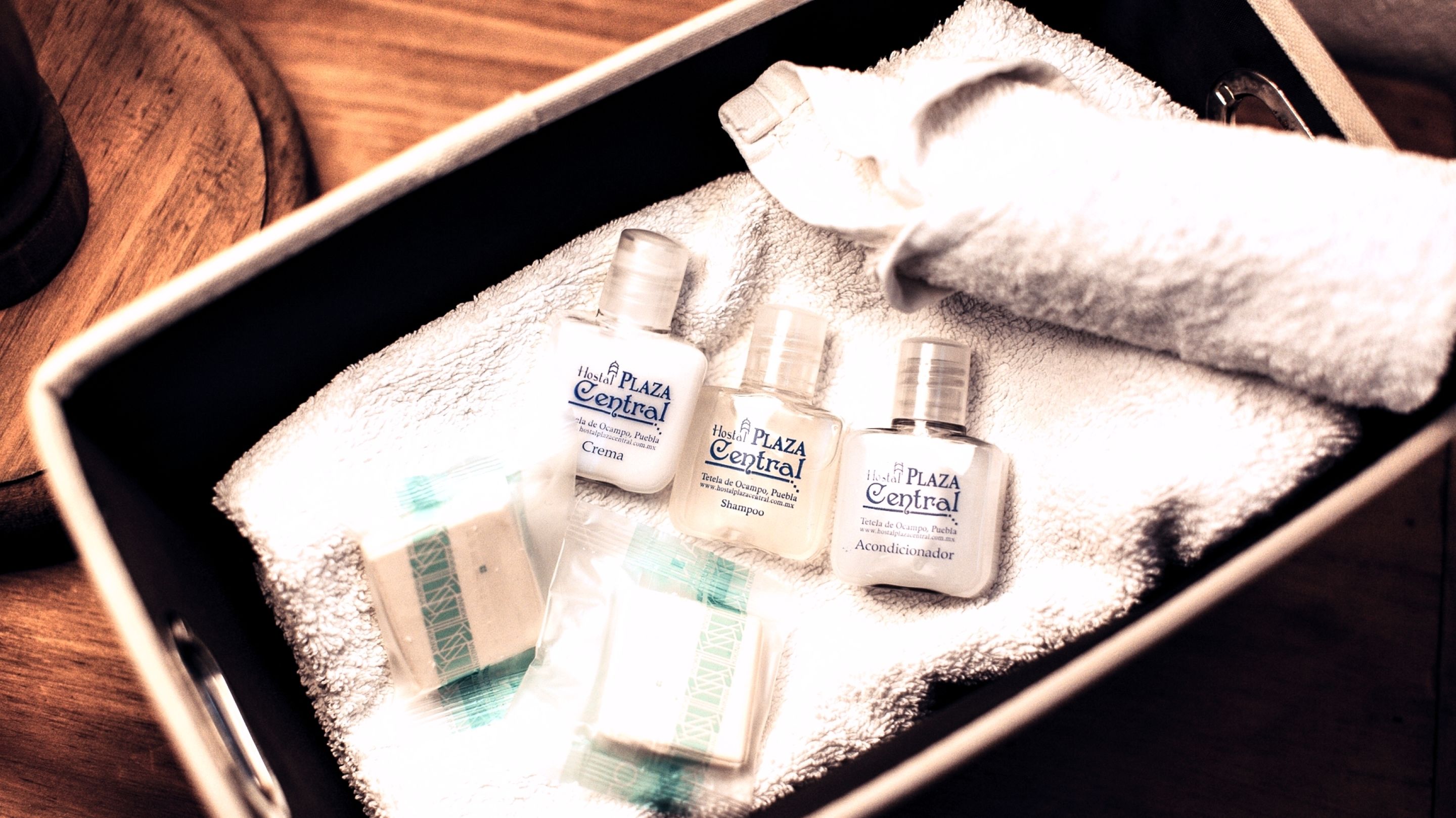 A metal tray with three bottles of shampoo and a folded towel.