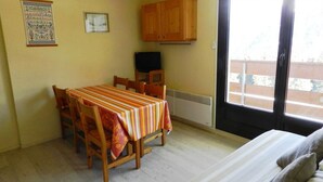 Una habitación con una mesa de comedor, sillas, una cama, un ventanal y un radiador.