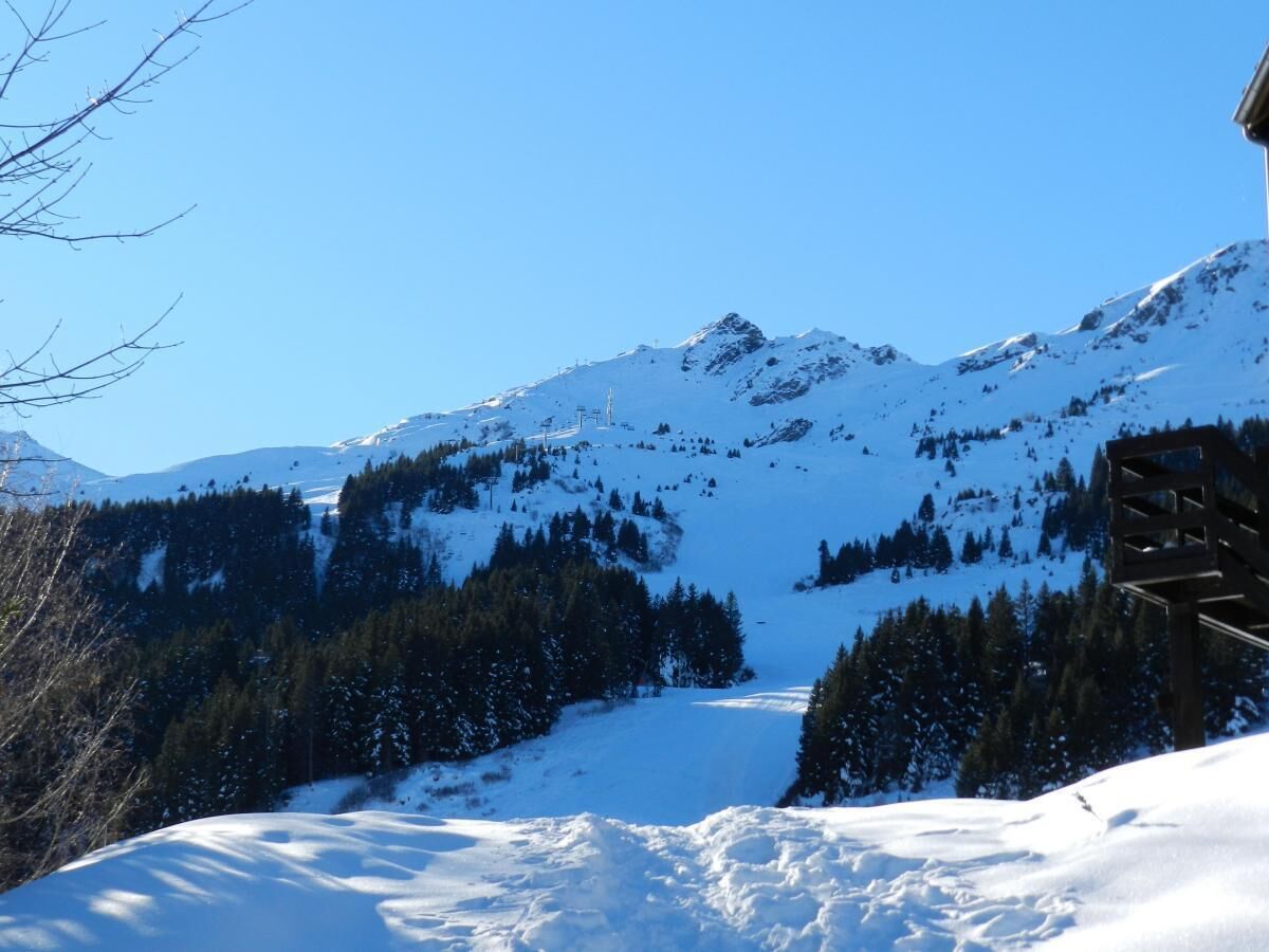 A snow-covered mountain landscape with a wooden structure, likely a chalet, in the foreground.